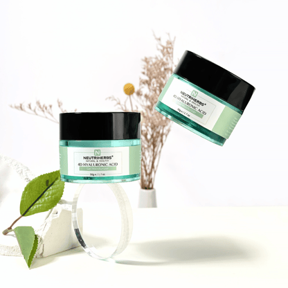 Življenjski slogovni posnetek Neutriherbs 4D Hyaluronic Acid Gel Moisturizer 50 g. Dva lončka vlažilne gel kreme sta predstavljena v svetlem in elegantnem okolju z naravnimi detajli, ki izražajo svežo rutino nege kože in intenzivno vlaženje.